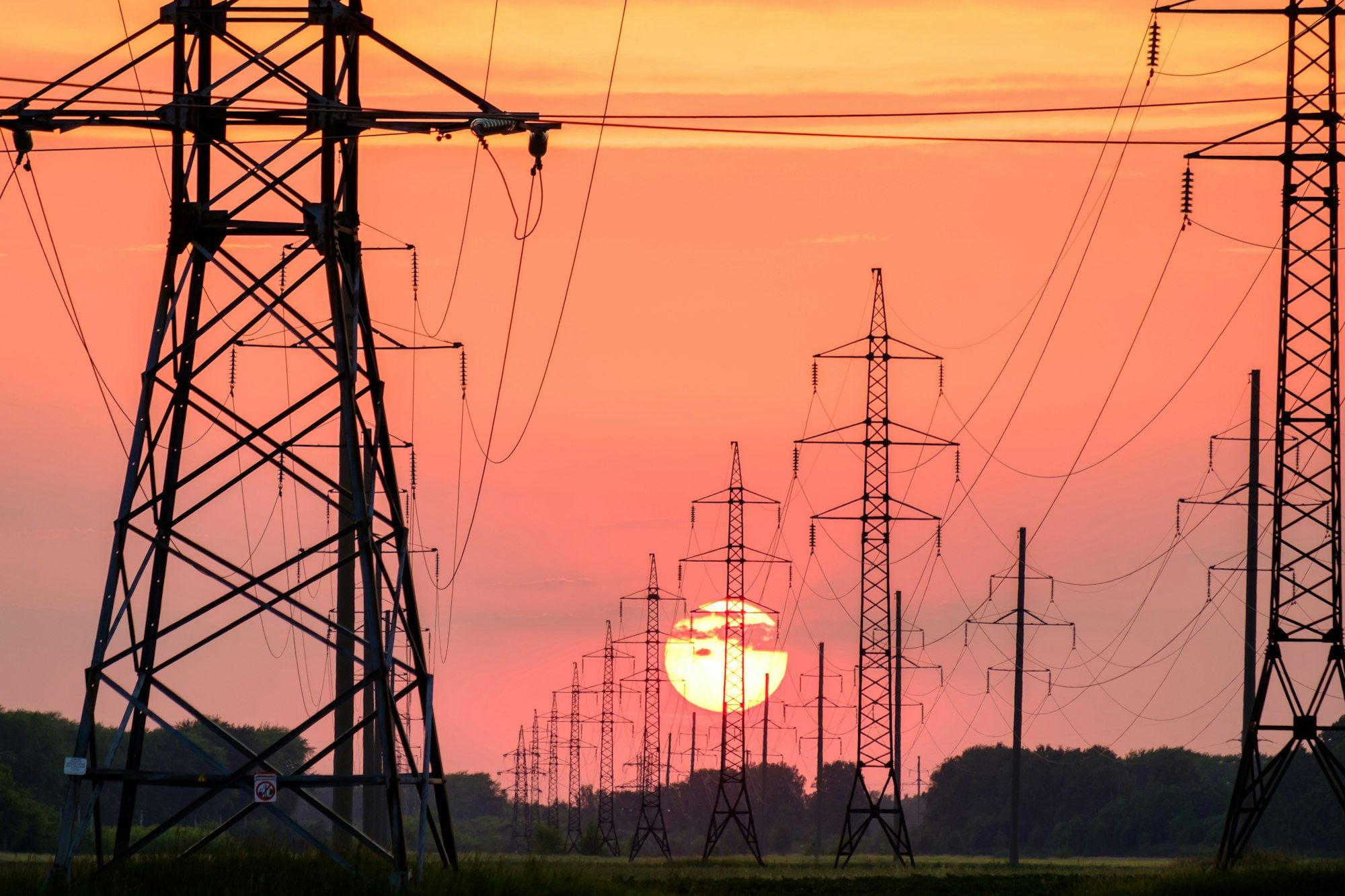Transmission towers before a giant setting sun
